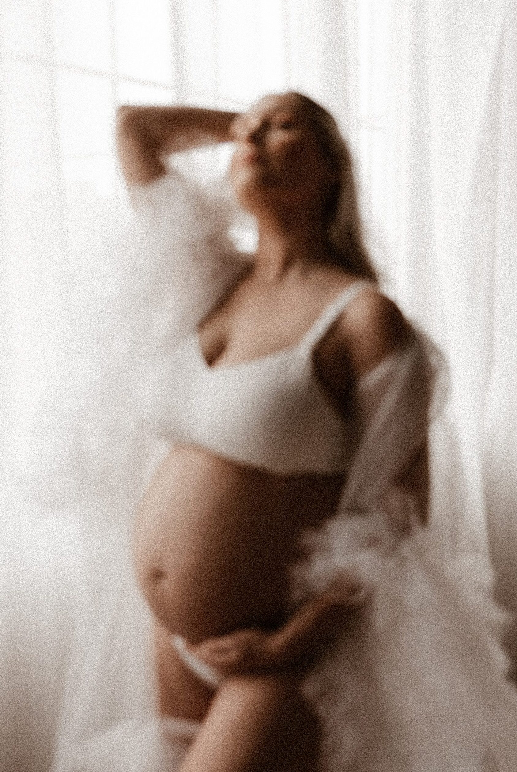 out of focus shot of expecting mother holding her belly photography studio Saint Louis Missouri
