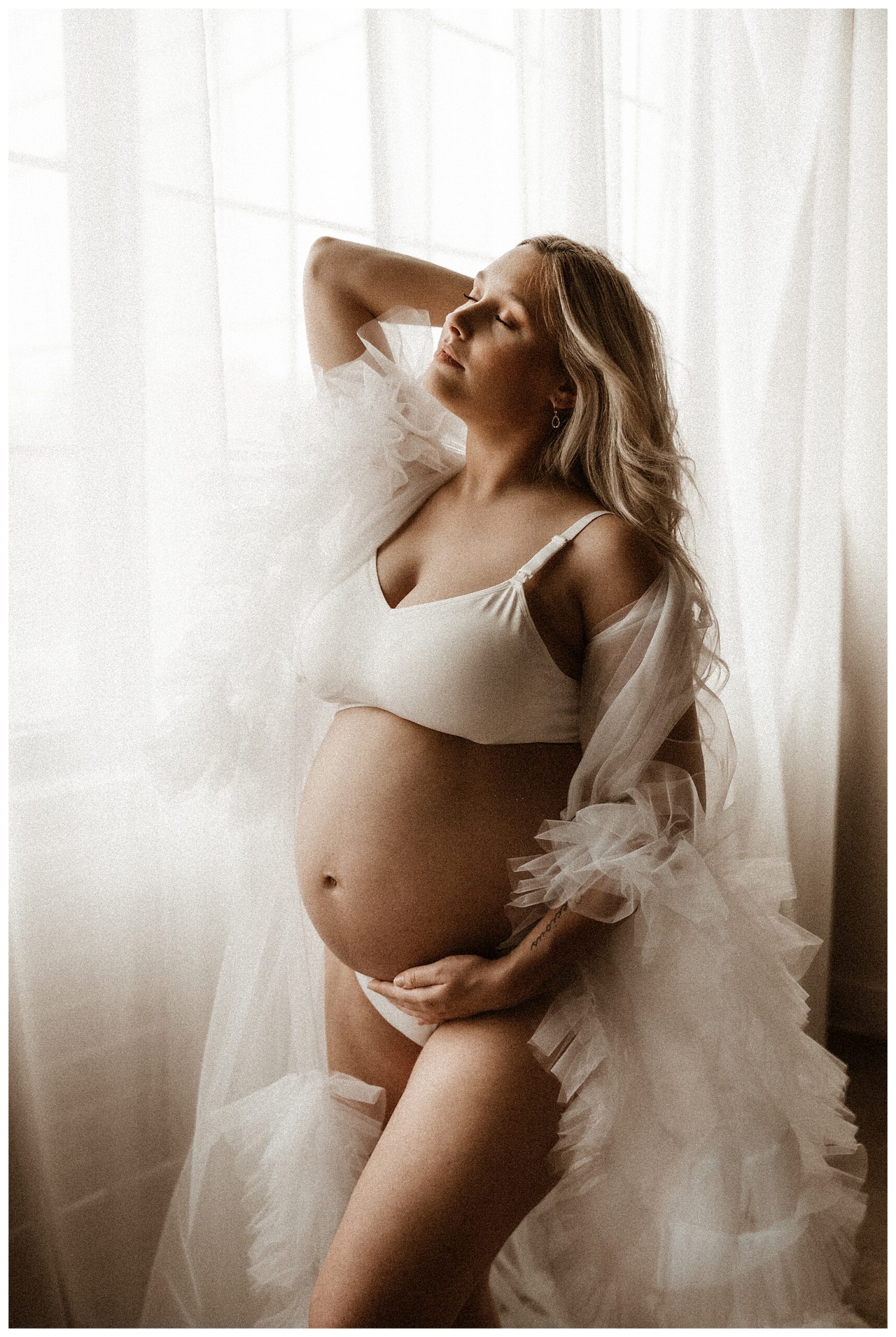 pregnant woman in sheer robe in front of curtains closing eyes during maternity session with fine art maternity photographer Rebecca Stephenson Photography O'fallon Missouri
