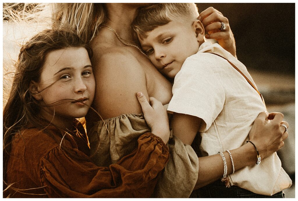 closeup of mother holding her two children at windy beach session in Oregon at Stormy Solis workshop Rebecca Stephenson fine art family photographer St Louis Missouri