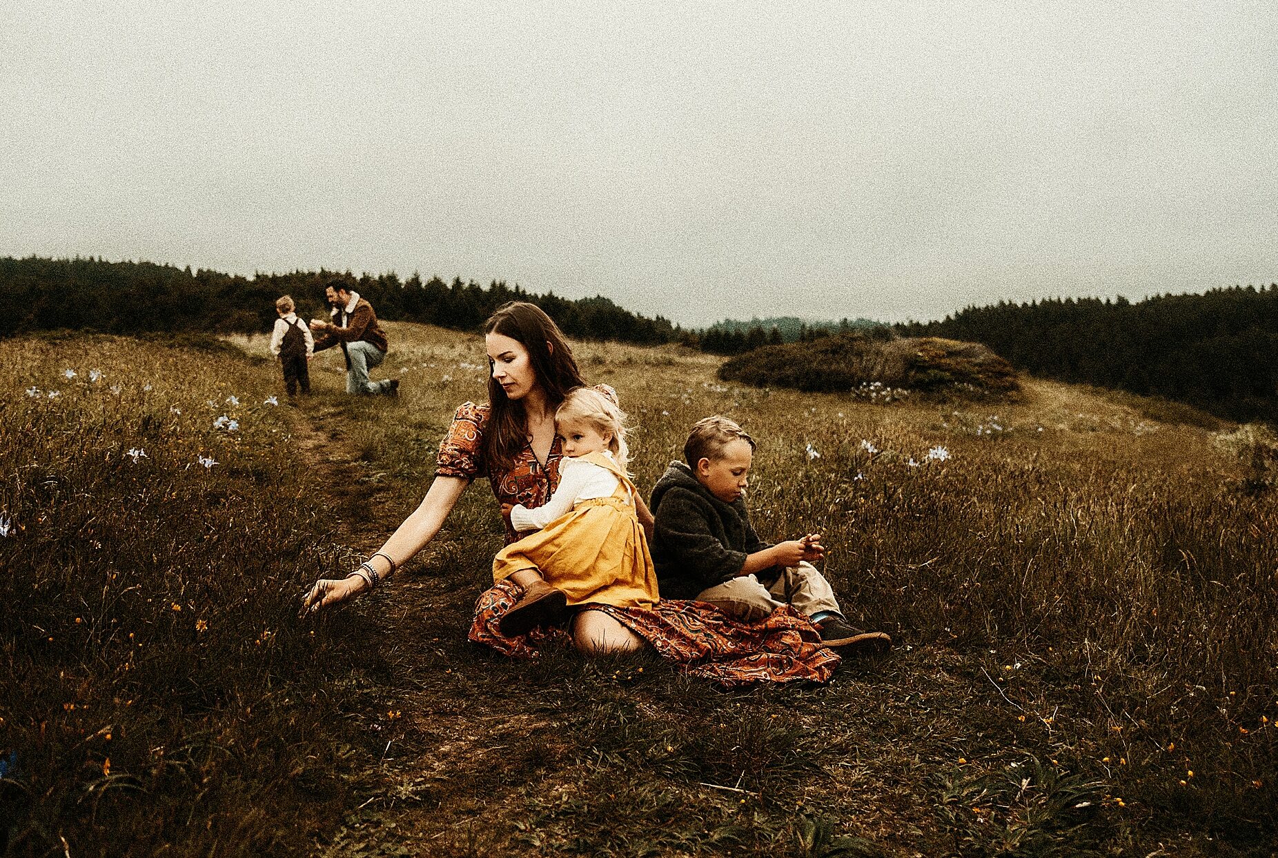 Moody and heartfelt portrait of mother picking flowers with her children fine art luxury photography