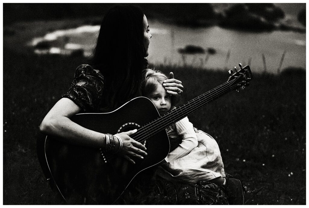 black and white portrait of mother holding her daughter and playing the guitar at family session in Oregon