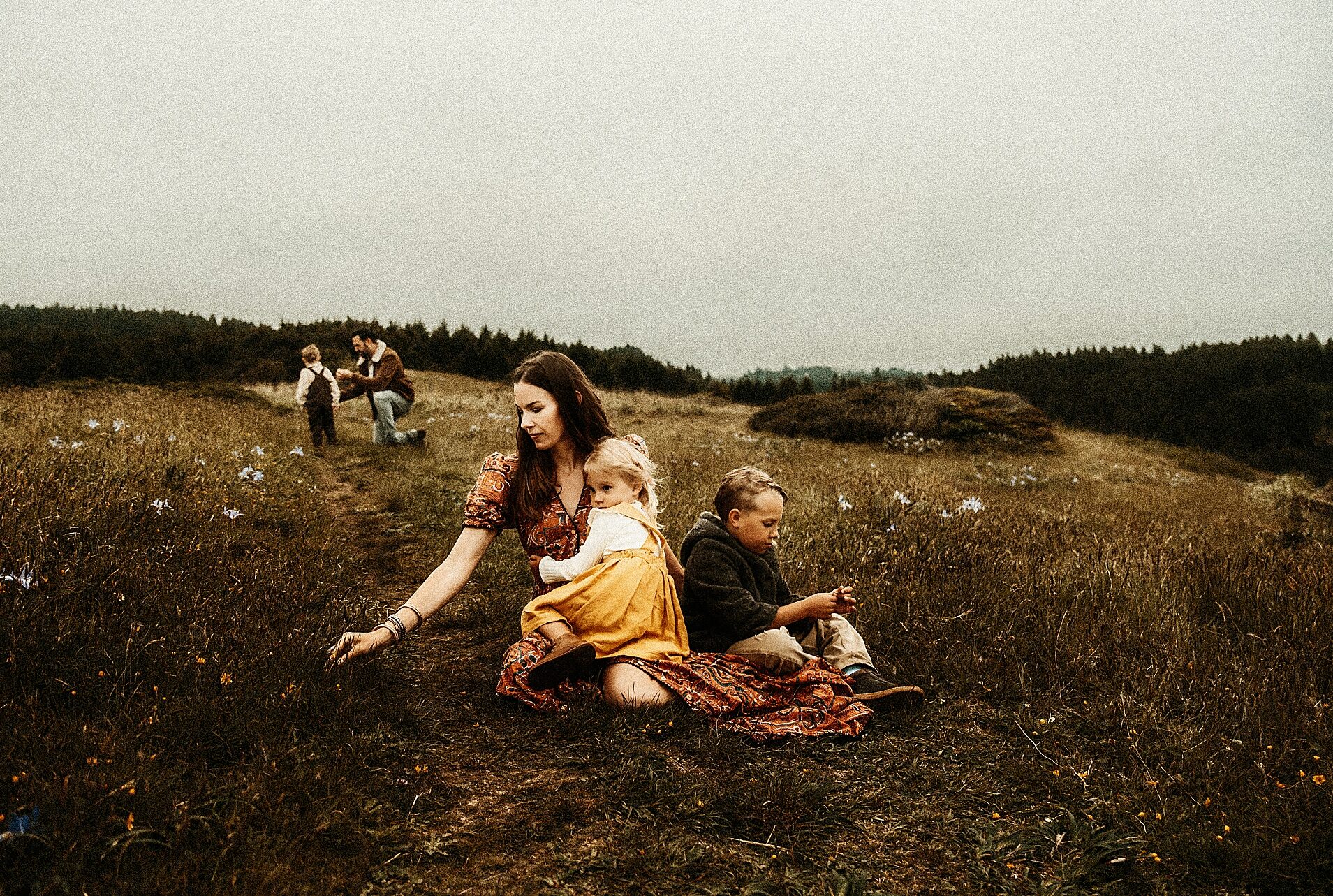 Moody and heartfelt portrait of mother picking flowers with her children fine art luxury photography