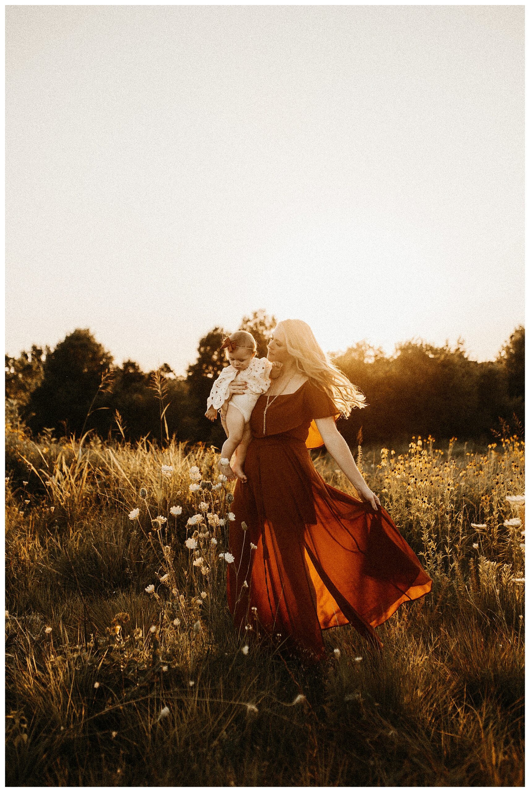 Mom dancing with baby daughter in orange Baltic Born dress at sunset family session in Wildflower Field O'fallon Missouri