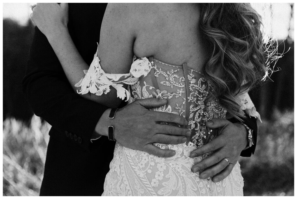 black and white close up grooms hands on brides back