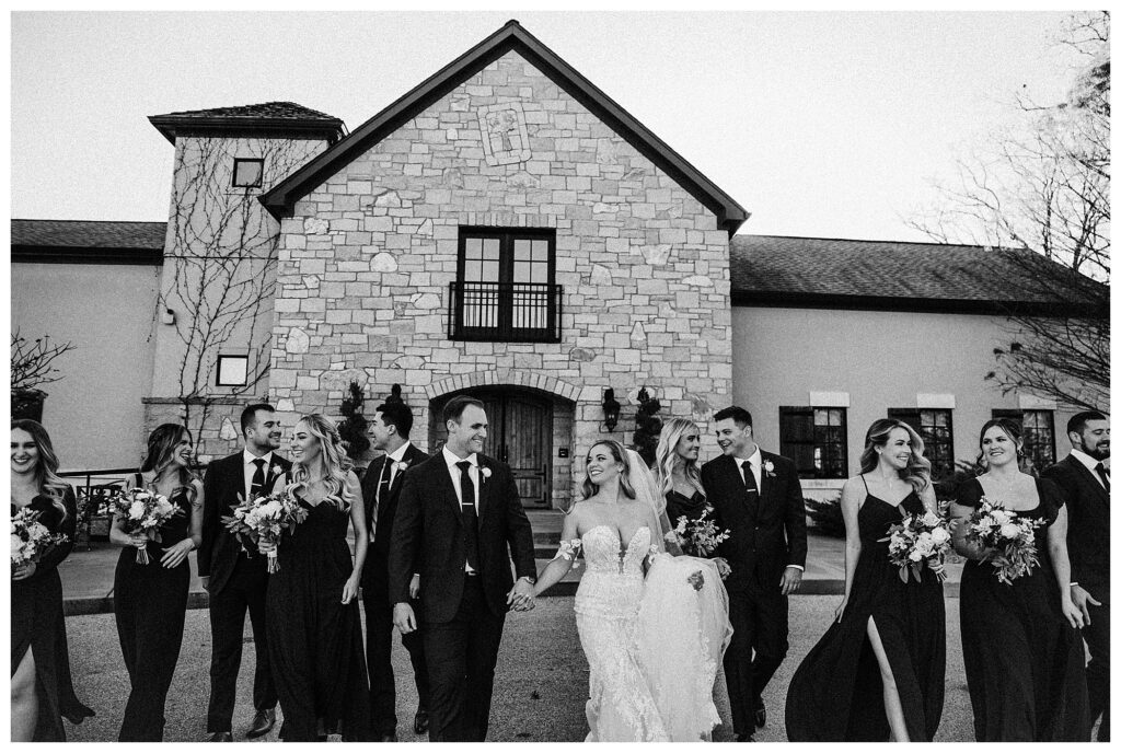 black and white wedding party walking in front of venue