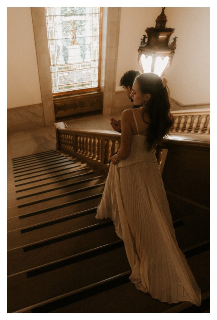 couple walking down staircase grainy engagement session Central Library St. Louis